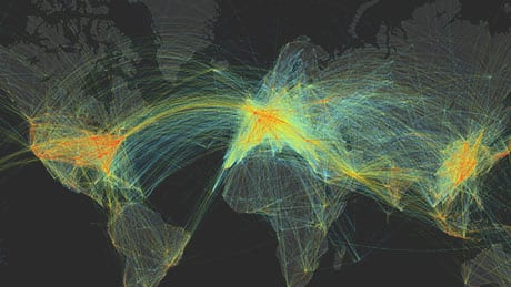 Colorful arcing lines showing air traffic flow on a world map created with geospatial technology