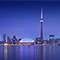Toronto skyline illuminated at night, featuring tall buildings and the CN Tower against a dark sky.