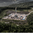 An aerial view of an oil drilling rig situated in the center of a dense forest