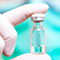 Close-up of a gloved hand holding a vaccine vial