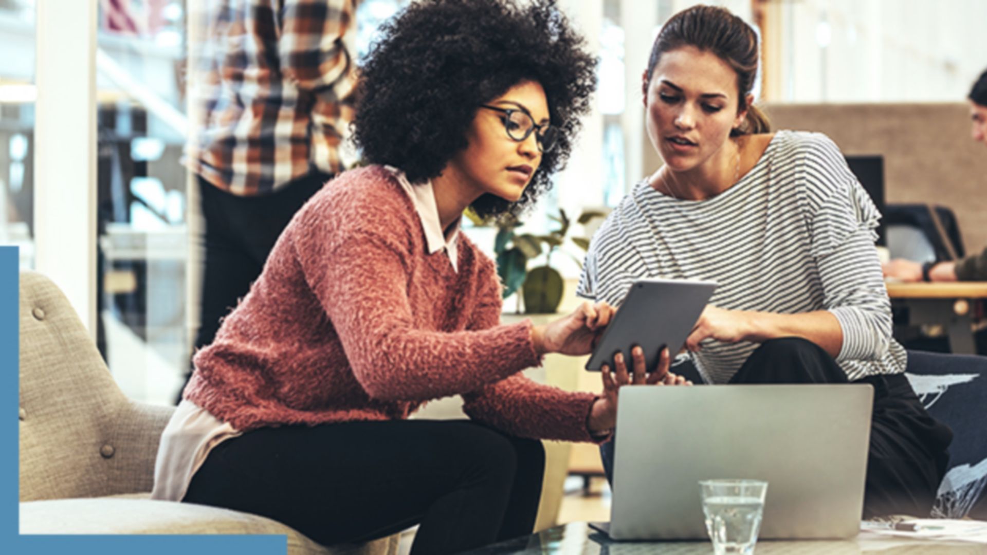 Two people sitting in a coffee shop working with GIS software on a tablet and laptop