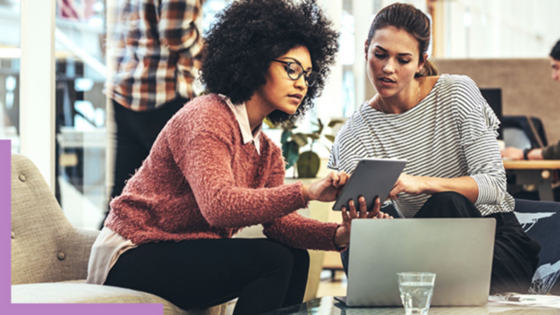 Two people sitting in a coffee shop working with GIS software on a tablet and laptop
