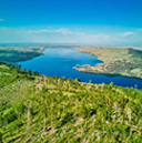  Aerial image of a smooth blue river winding through a landscape of wild green hills under a clear blue sky