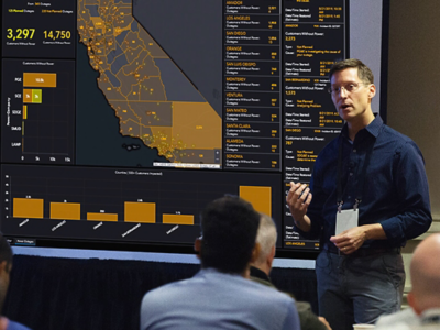  Speaker giving a presentation with a map and a dashboard of statistics relating to the state of California