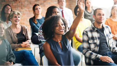A gathering of people with one raising her hand